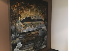 Een schilderij van een grot met stalactieten en -stalagmieten.