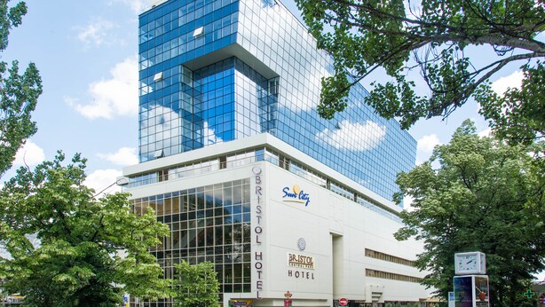 Un hôtel moderne avec une façade en verre, une enseigne indiquant le Bristol Hotel et le logo de Sun City.