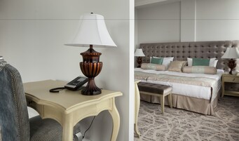 Una habitación de hotel con una cama, mesitas de noche, una lámpara, un teléfono y una silla.