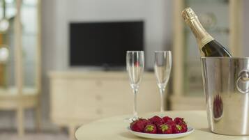 A table with a bottle of champagne, two glasses, and a plate of strawberries.
