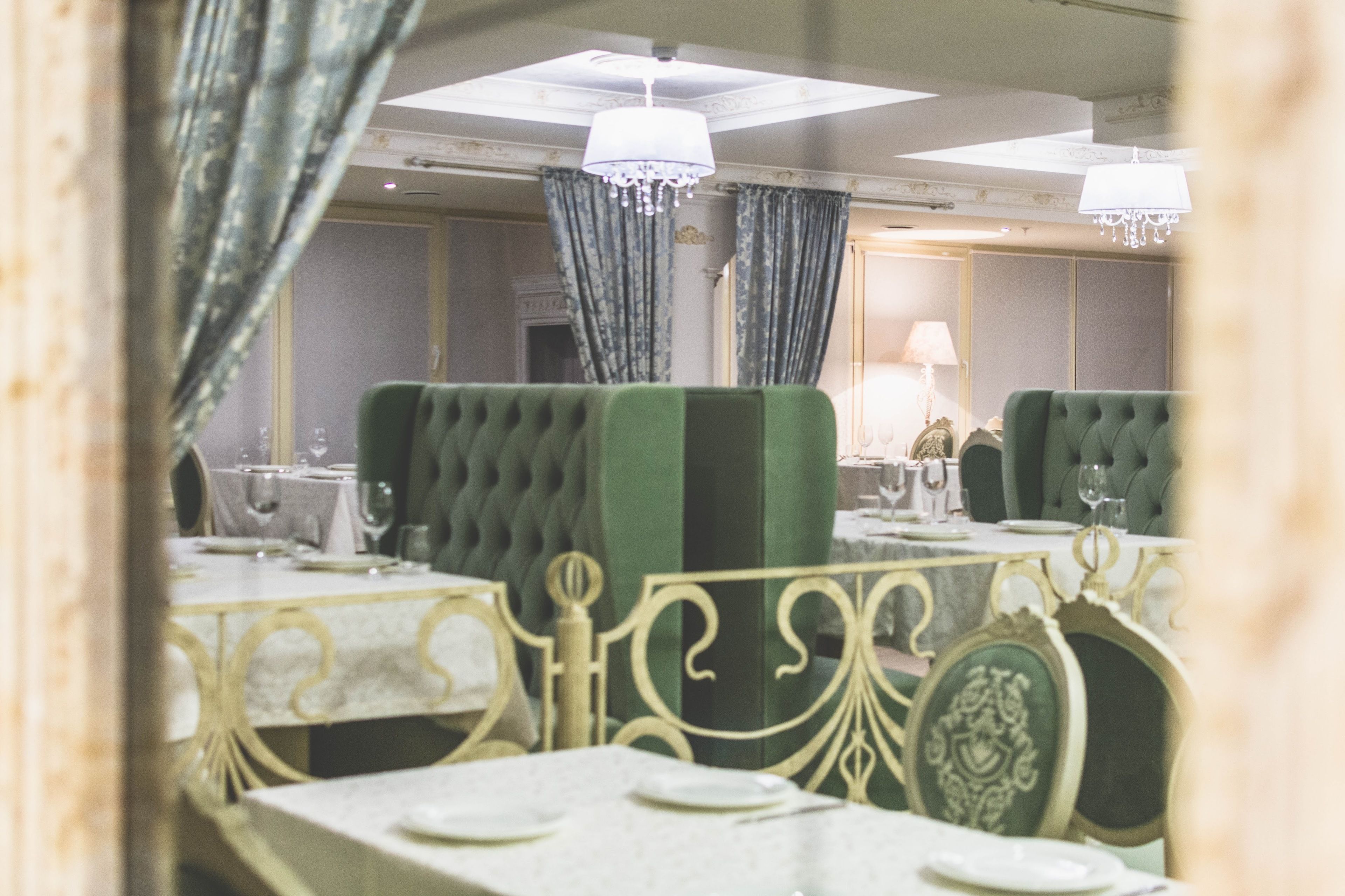 Comedor con sillas tapizadas de verde, vajilla blanca y candelabros.