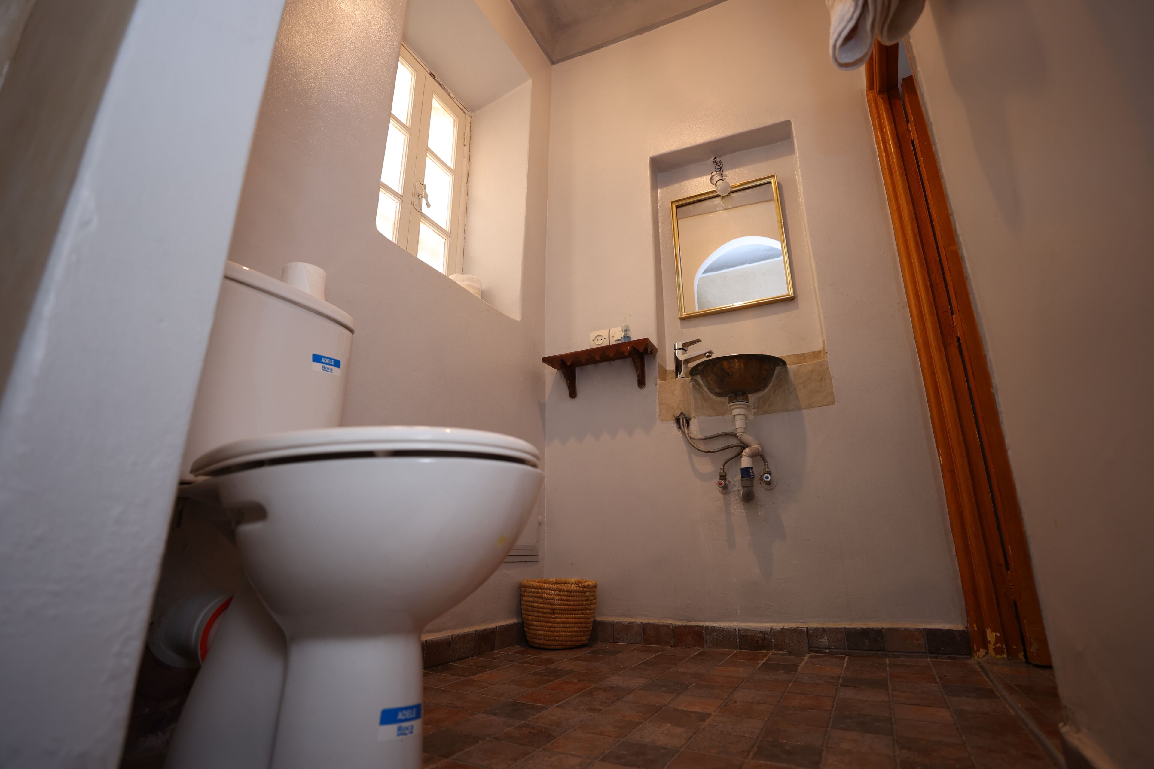 Ein Badezimmer mit Toilette, Waschbecken, Spiegel und Fenster.