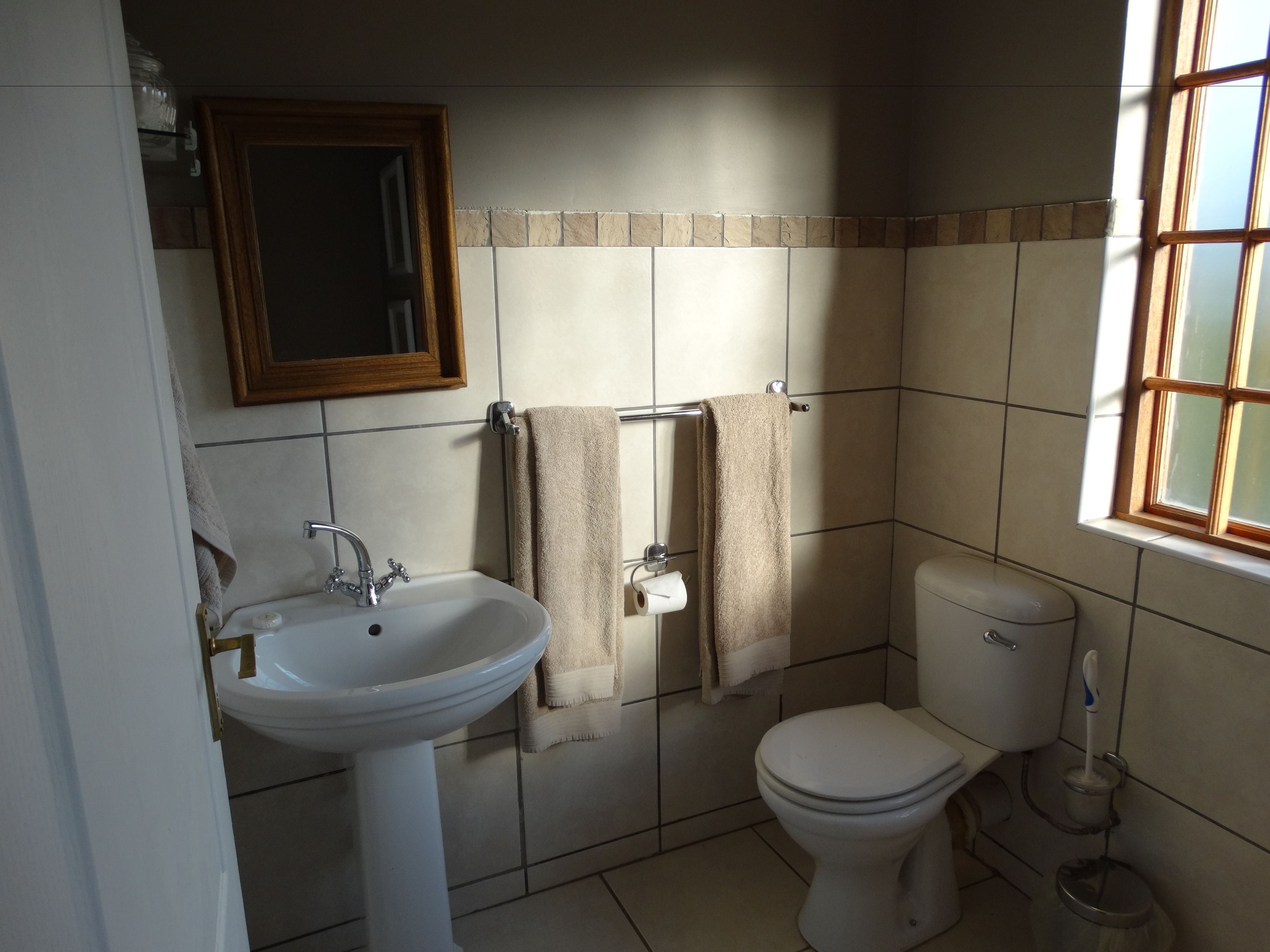 A bathroom with a sink, toilet, and a window.