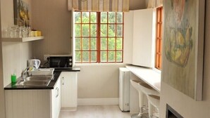Cocina moderna con armarios blancos, microondas integrado y ventana con vistas a zonas verdes.