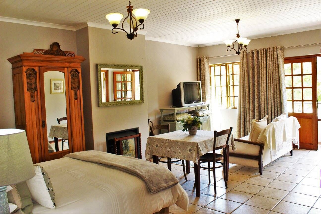 Habitación de hotel con cama, escritorio con televisor, mesa de comedor con sillas, espejo y candelabro.