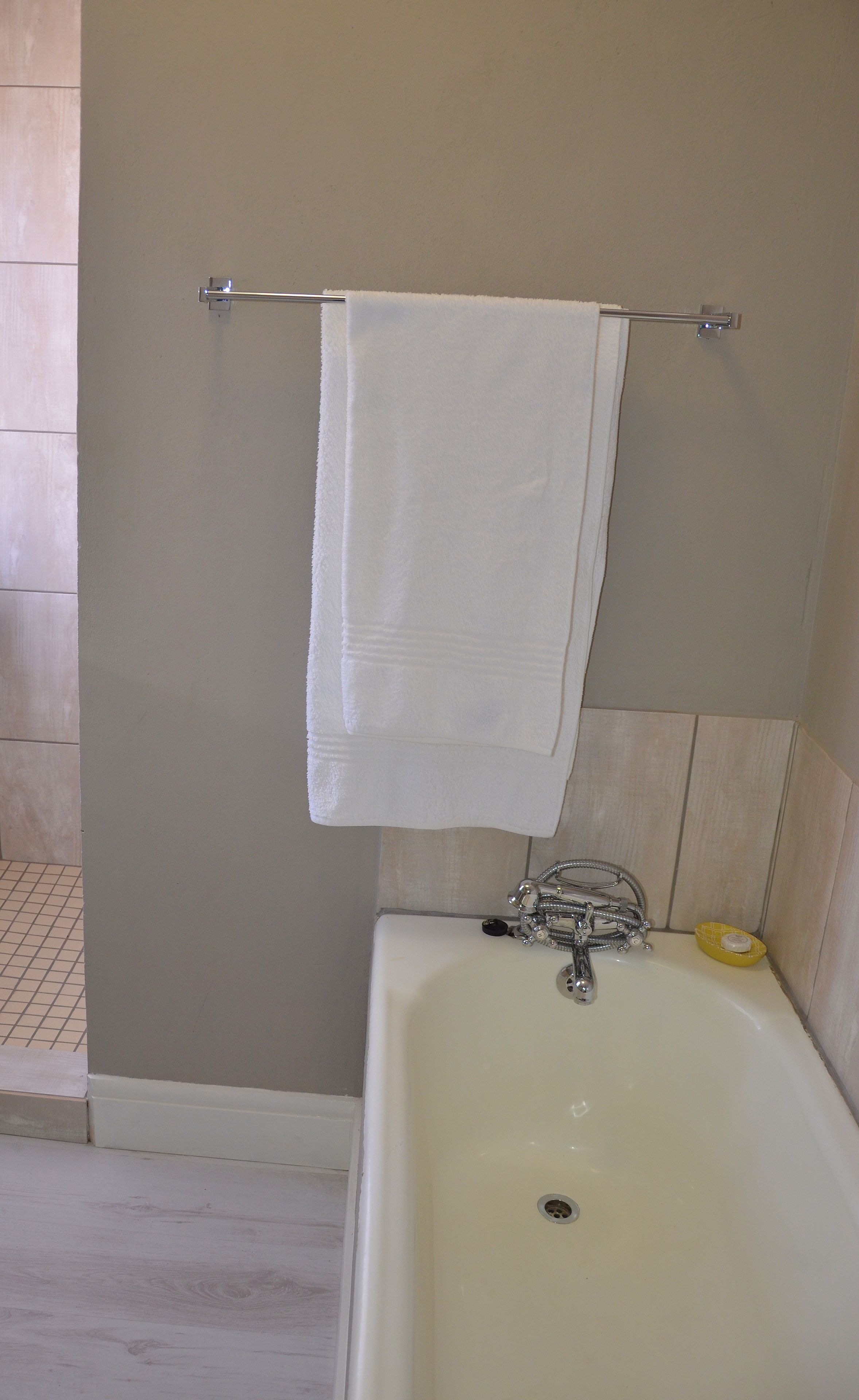 A bathroom with a bathtub, a towel rack with a white towel, and a yellow soap dish.