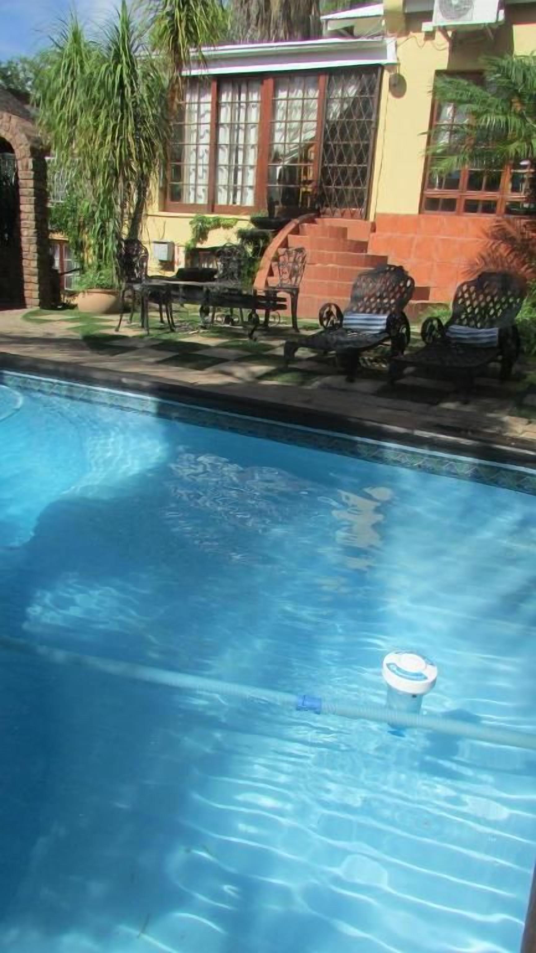 Una piscina con sillas de descanso y un área de terraza.