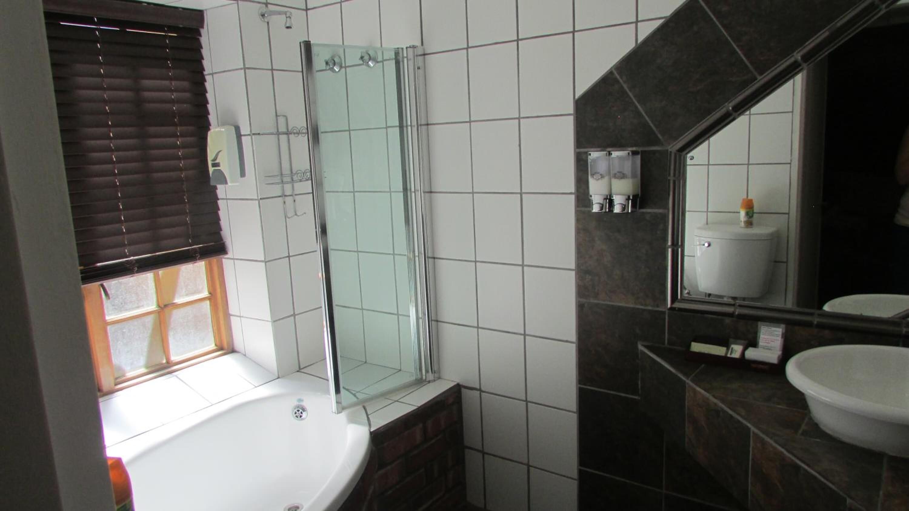 A bathroom with a bathtub, a glass shower enclosure, a toilet, and a sink.
