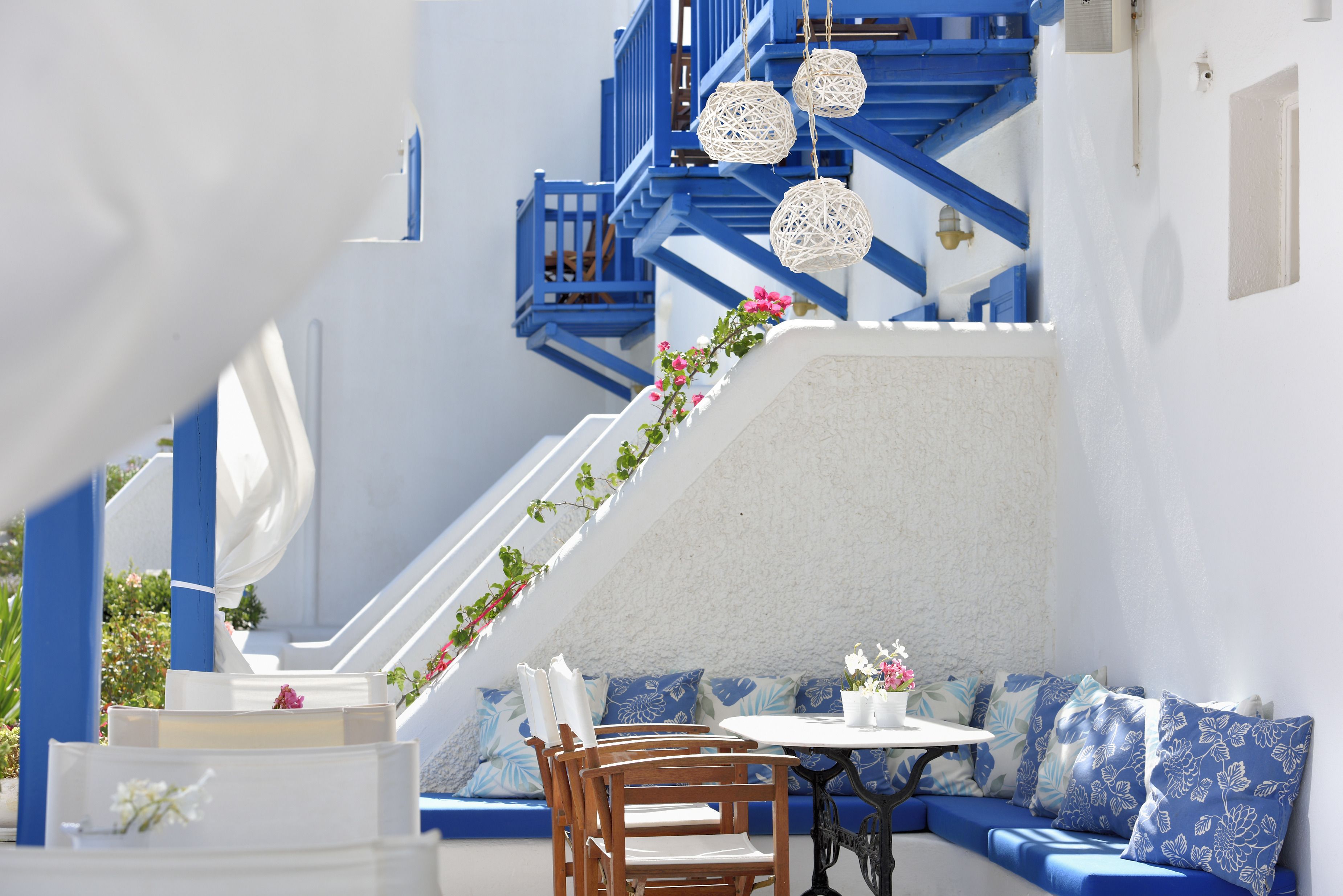 Ein sonnendurchflutetes Interieur mit einer blauen Treppe, weißen Wänden und einem runden Tisch mit Stühlen.