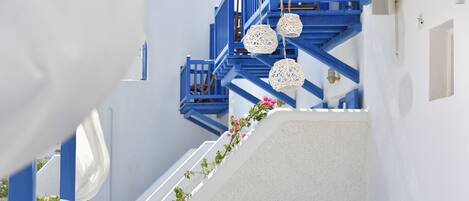 Ein sonnendurchflutetes Interieur mit einer blauen Treppe, weißen Wänden und einem runden Tisch mit Stühlen.