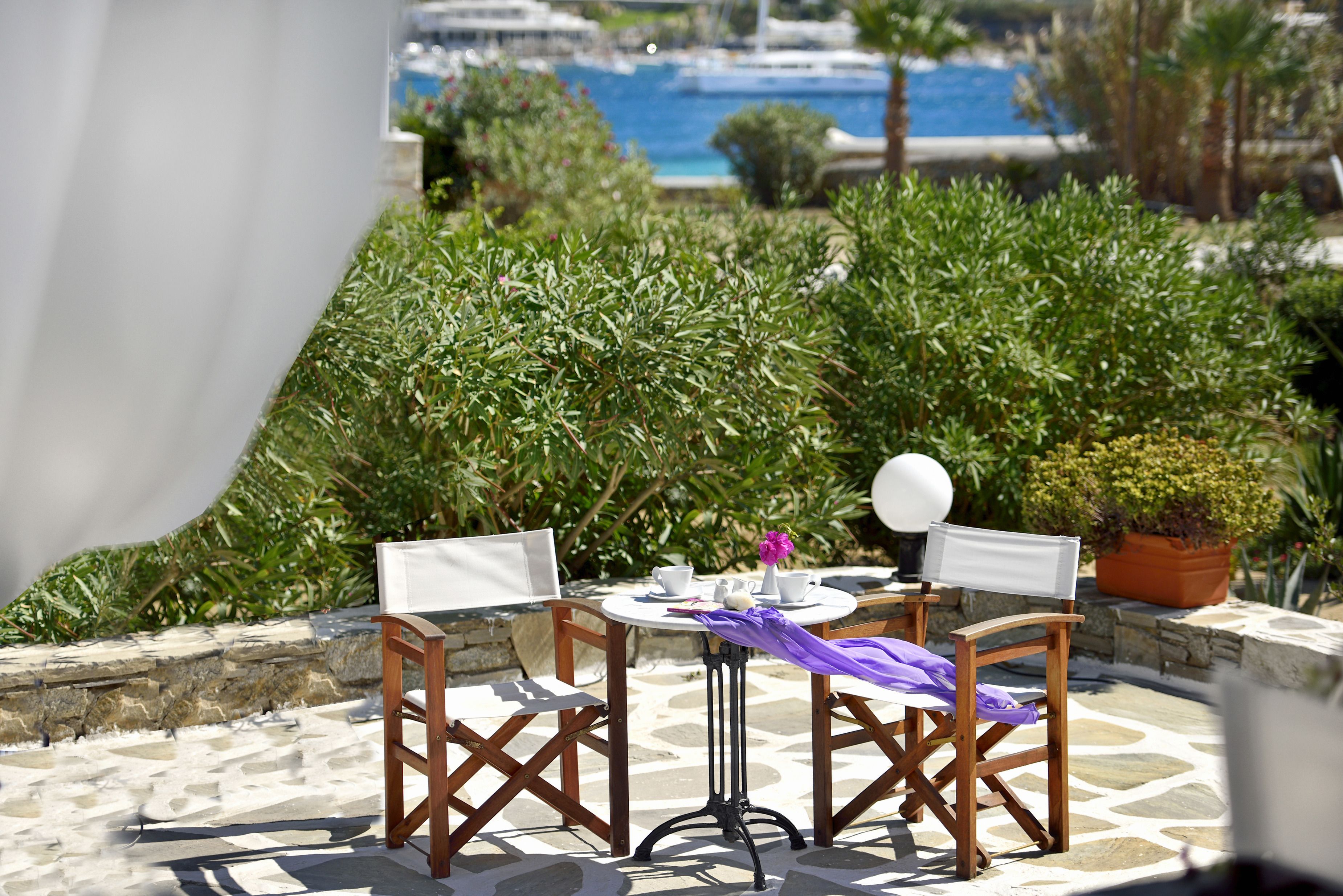 Une terrasse avec deux chaises en bois, une petite table ronde et un pot de fleurs.