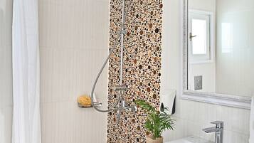 A bathroom with a shower, a sink, and a mirror.