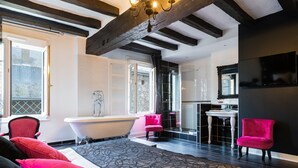 A modern bathroom with a freestanding bathtub, a vanity with a mirror, and a shower area. -  Logis Hôtel Restaurant Le Cheval Blanc (Blere)