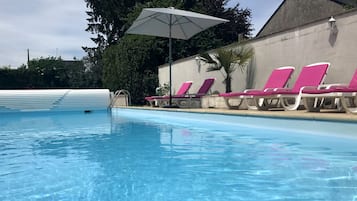 Een buitenzwembad en ligstoelen