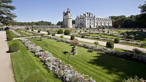 A formal garden with manicured lawns, geometric hedges, and a central tower. -  Logis Hôtel Restaurant Le Cheval Blanc (Blere)
