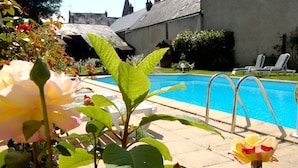 A swimming pool area with lounge chairs and a building in the background. -  Logis Hôtel Restaurant Le Cheval Blanc (Blere)