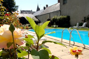 Un espace piscine avec des chaises longues et un bâtiment en arrière-plan.