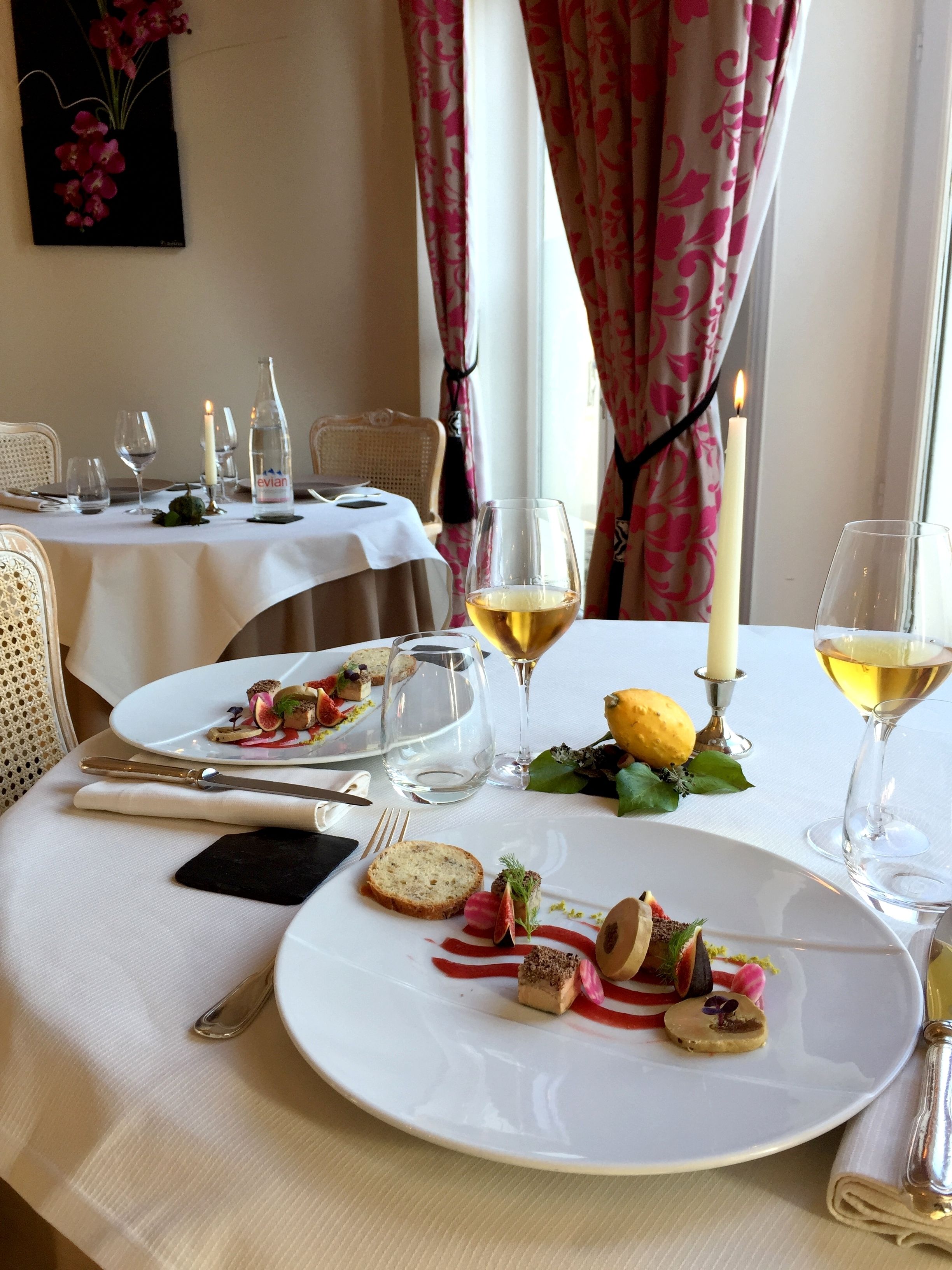 A dining table set with plates of food, wine glasses, and cutlery.