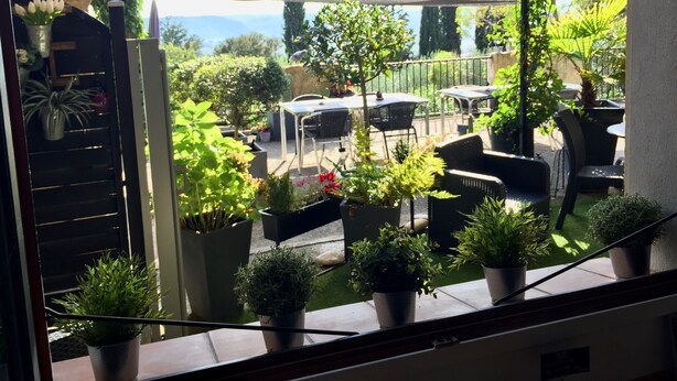 A terrace with outdoor seating, potted plants, and a view of the surrounding landscape. - Le Mas du Cadranier  (Villeneuve)