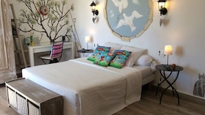 A bedroom with a large bed, two bedside tables, a dresser, a tree mural, and a wall with a bird mural. - Le Mas du Cadranier  (Villeneuve)