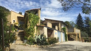 A traditional Mediterranean-style building with a stone facade, a small balcony, and a gravel driveway. - Le Mas du Cadranier  (Villeneuve)