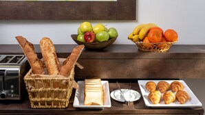 A breakfast buffet with bread, croissants, cheese, apples, oranges, and bananas. - Thomas Albert Hotel (Chisinau)