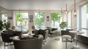 A modern interior with grey upholstered seating, round tables, and pendant lighting. - Thomas Albert Hotel (Chisinau)