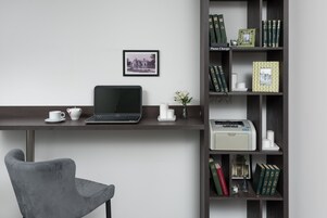 Un espacio de trabajo moderno con una computadora portátil, una taza, un florero con flores y una estantería con libros y objetos decorativos.