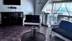 Et moderne opholdsområde med et fladskærms-tv, et spiseområde og et siddeområde med udsigt over byen.