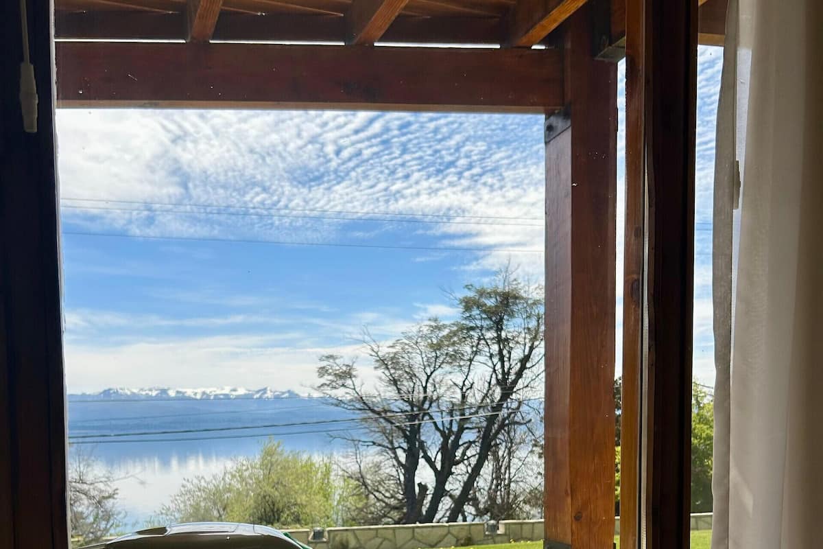 Vista a través de una ventana con una mesa lista para el té, una tetera y una cesta con objetos.