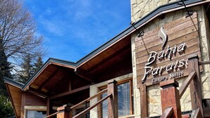 Un escalier en bois mène à un immeuble à la façade en pierre, sur lequel on peut lire l’inscription « Bahia Paradise Luxury Suites ».