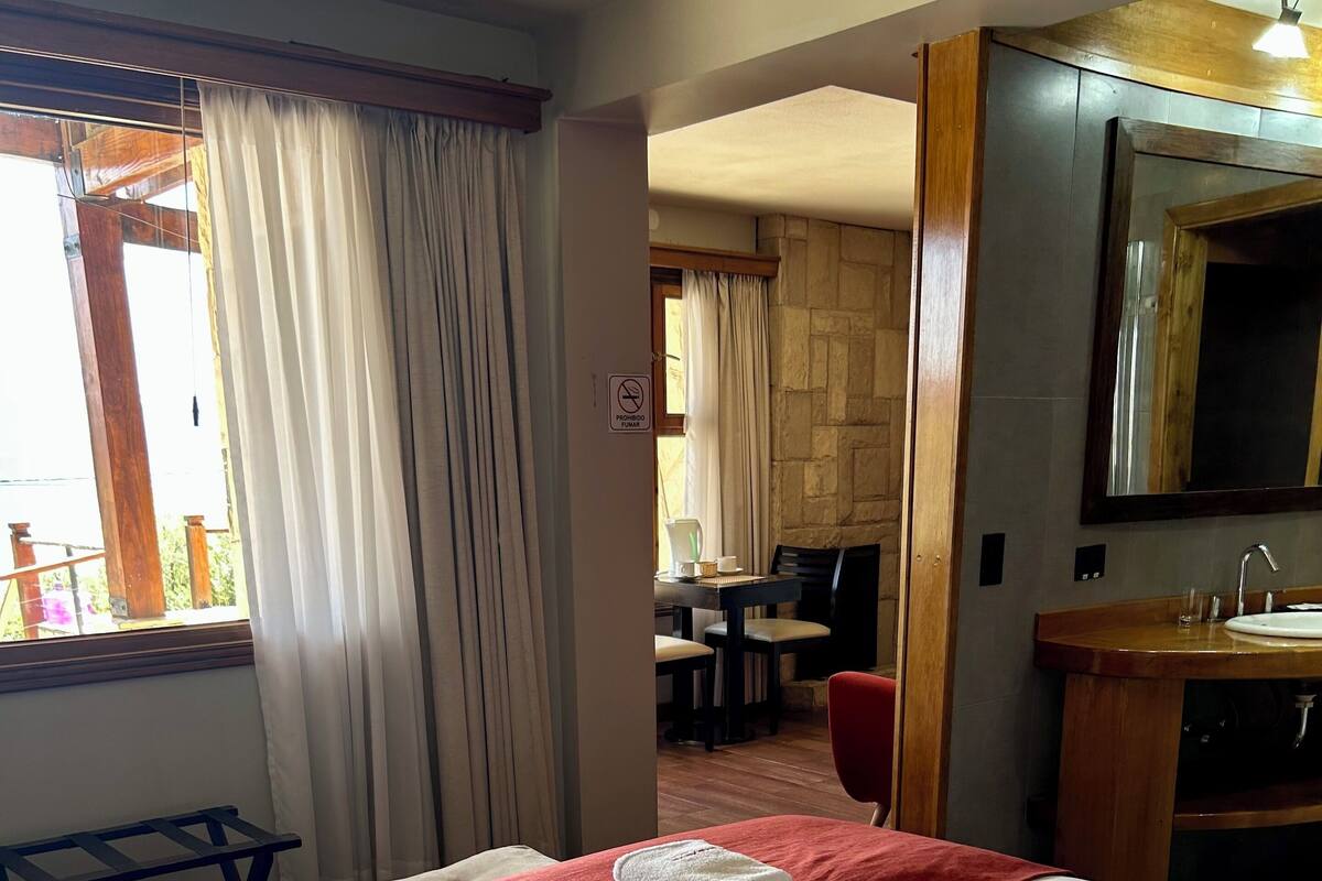 Una habitación de hotel con cama, baño y zona de comedor.