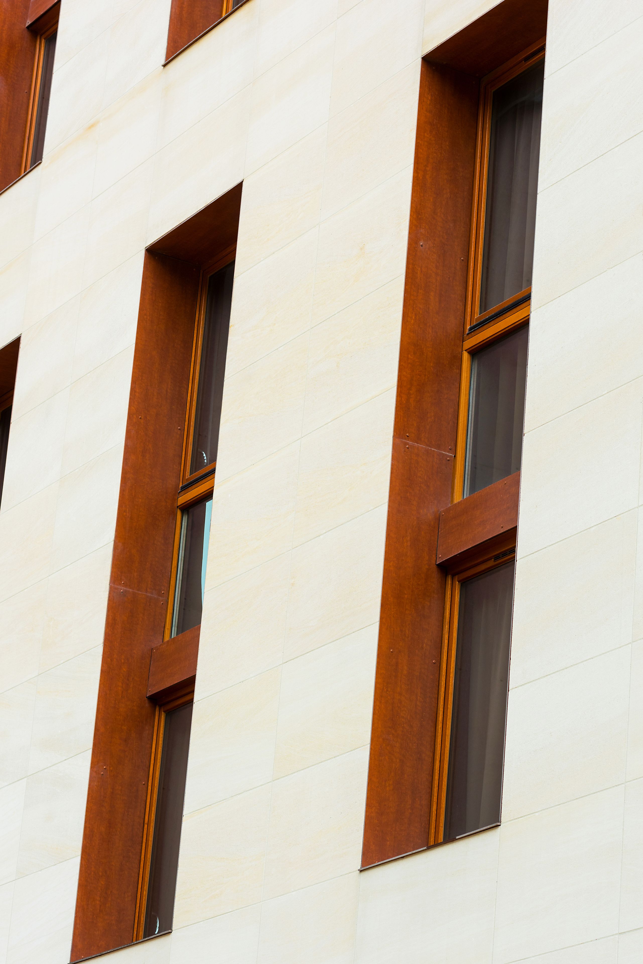 Une façade d’immeuble avec des fenêtres rectangulaires et des encadrements en bois.