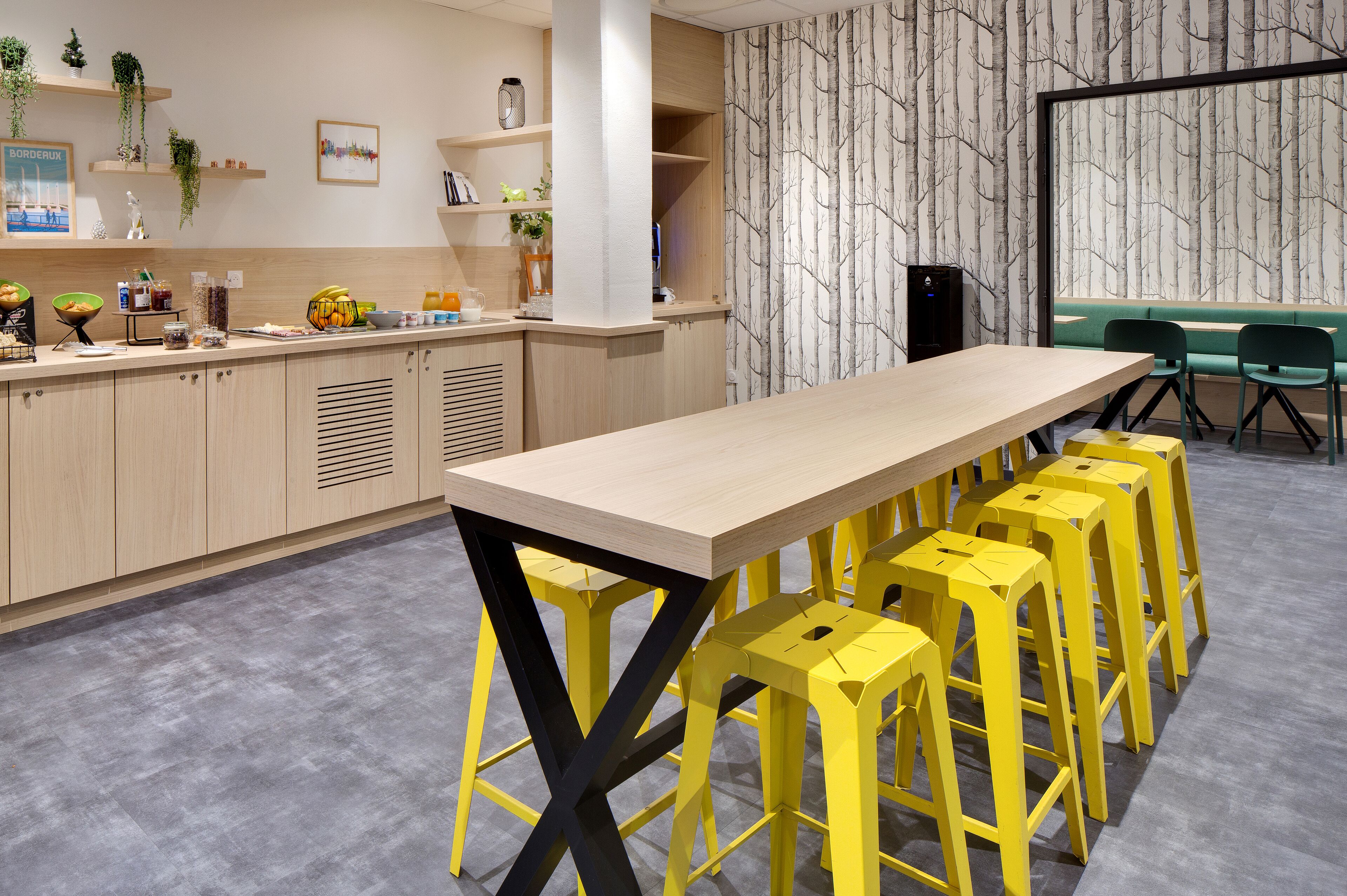A modern meeting room with a long table, yellow stools, and a large window with a view.