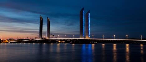 A bridge with illuminated structures and a calm water body.