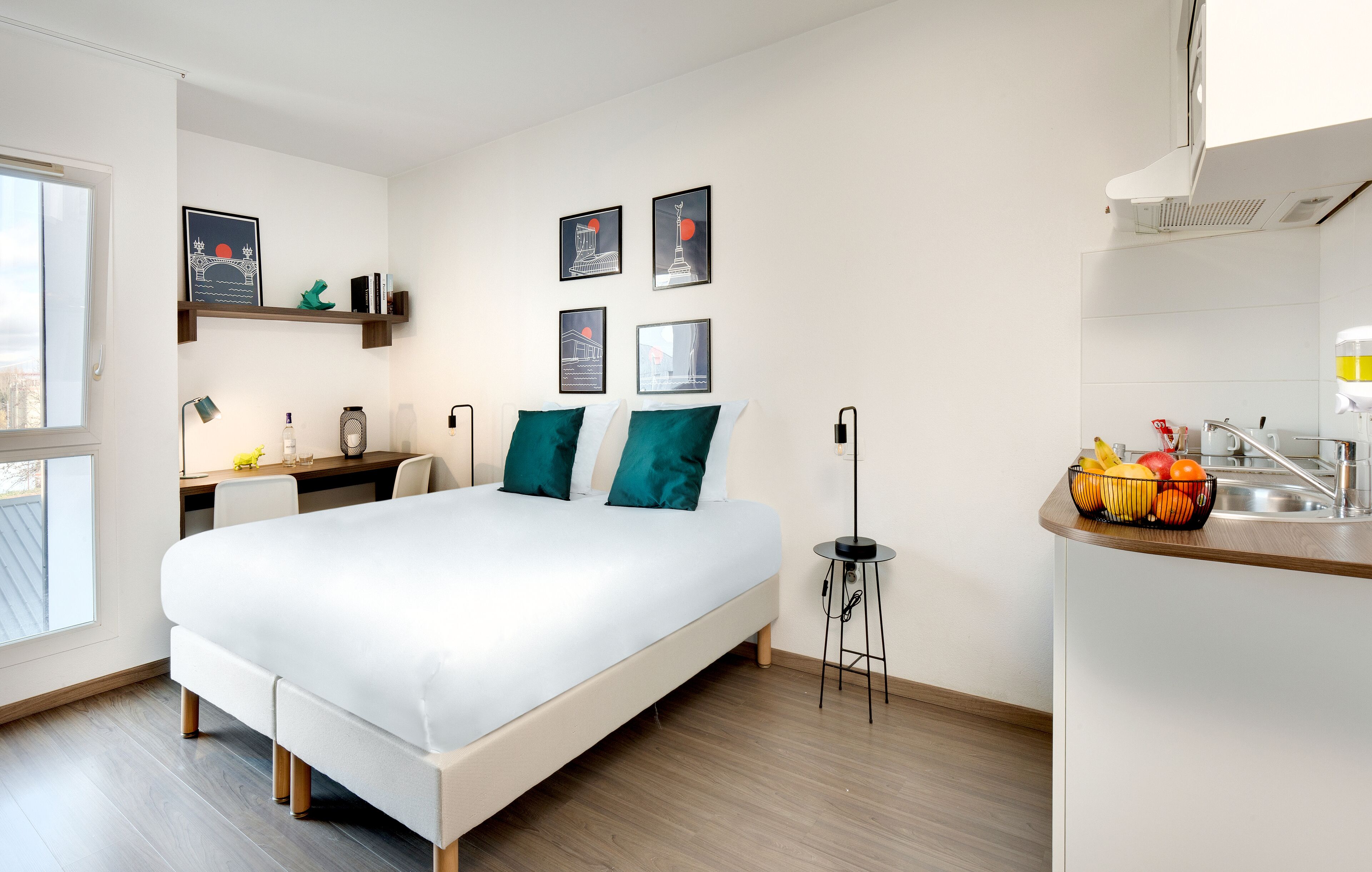 Ein modernes Schlafzimmer mit einem großen Bett, einem Schreibtisch und einer kleinen Küchenzeile.