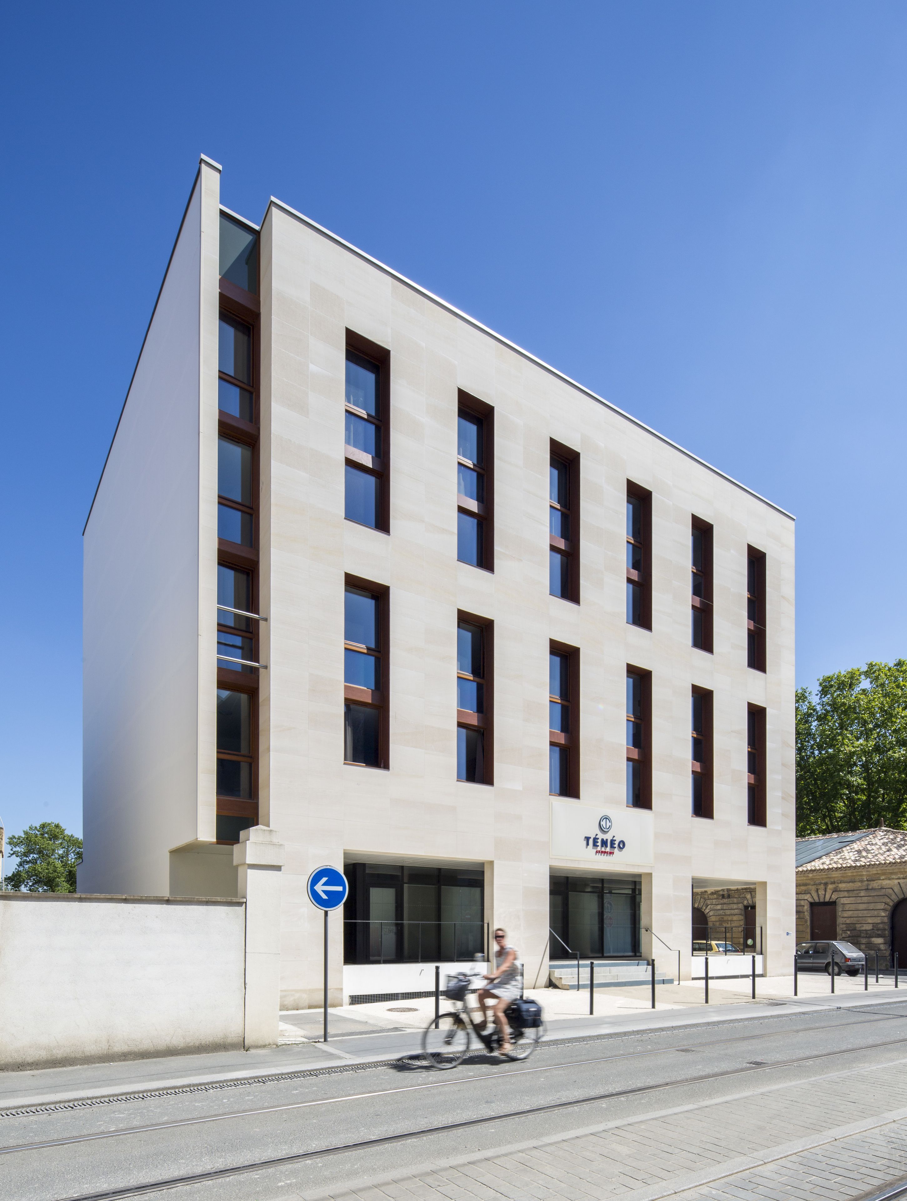 Un bâtiment moderne à la façade plate, doté de grandes fenêtres et d’une enseigne indiquant qu’il s’agit d’un hôtel.