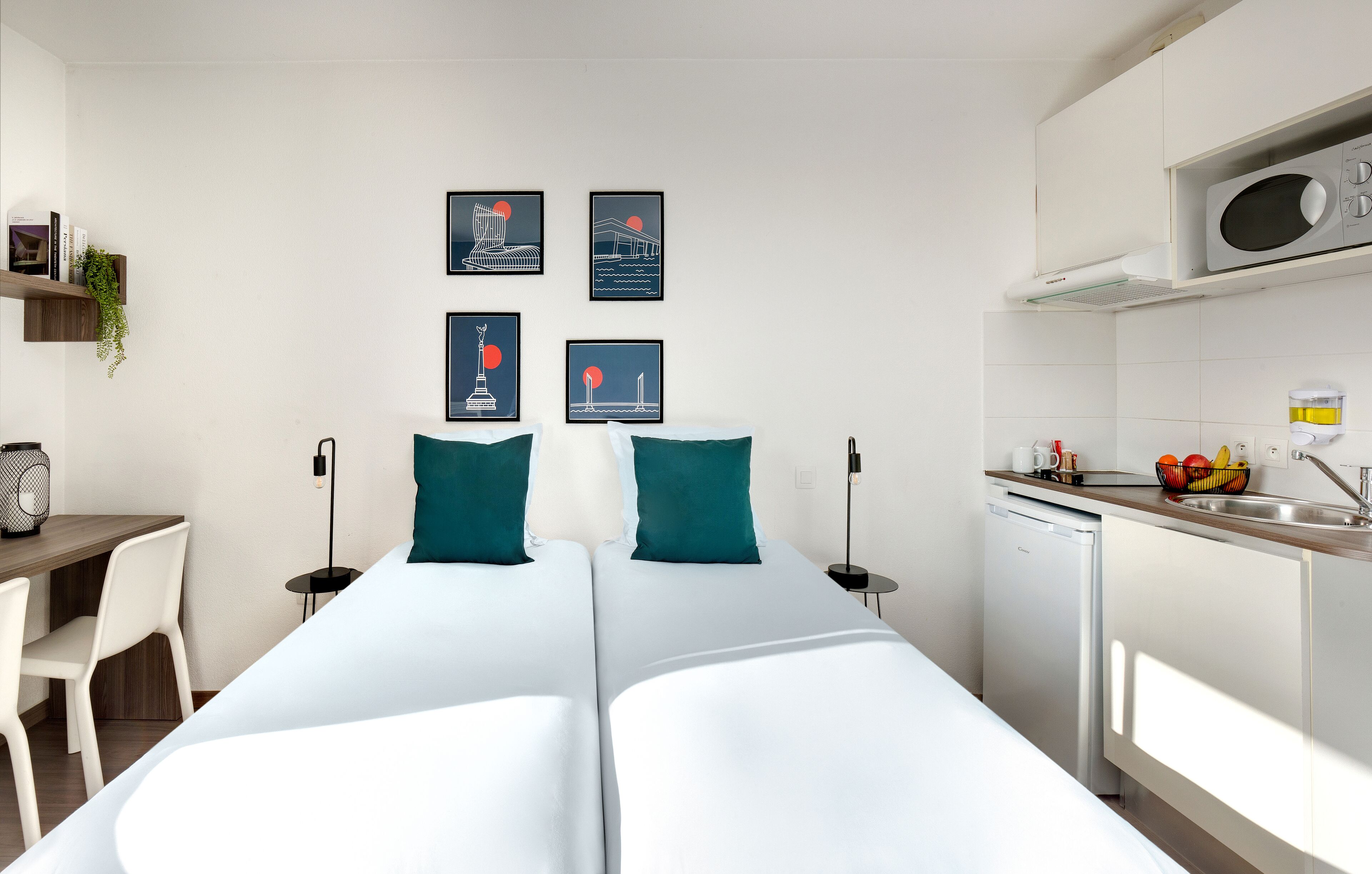 Een moderne hotelkamer met een bed, een bureau en een kitchenette.