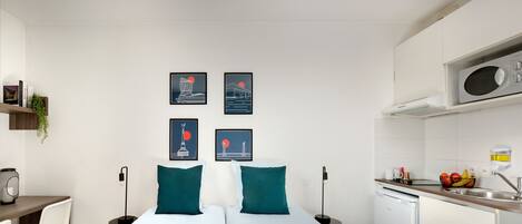 Ett modernt hotellrum med en säng, ett skrivbord och ett litet pentry.