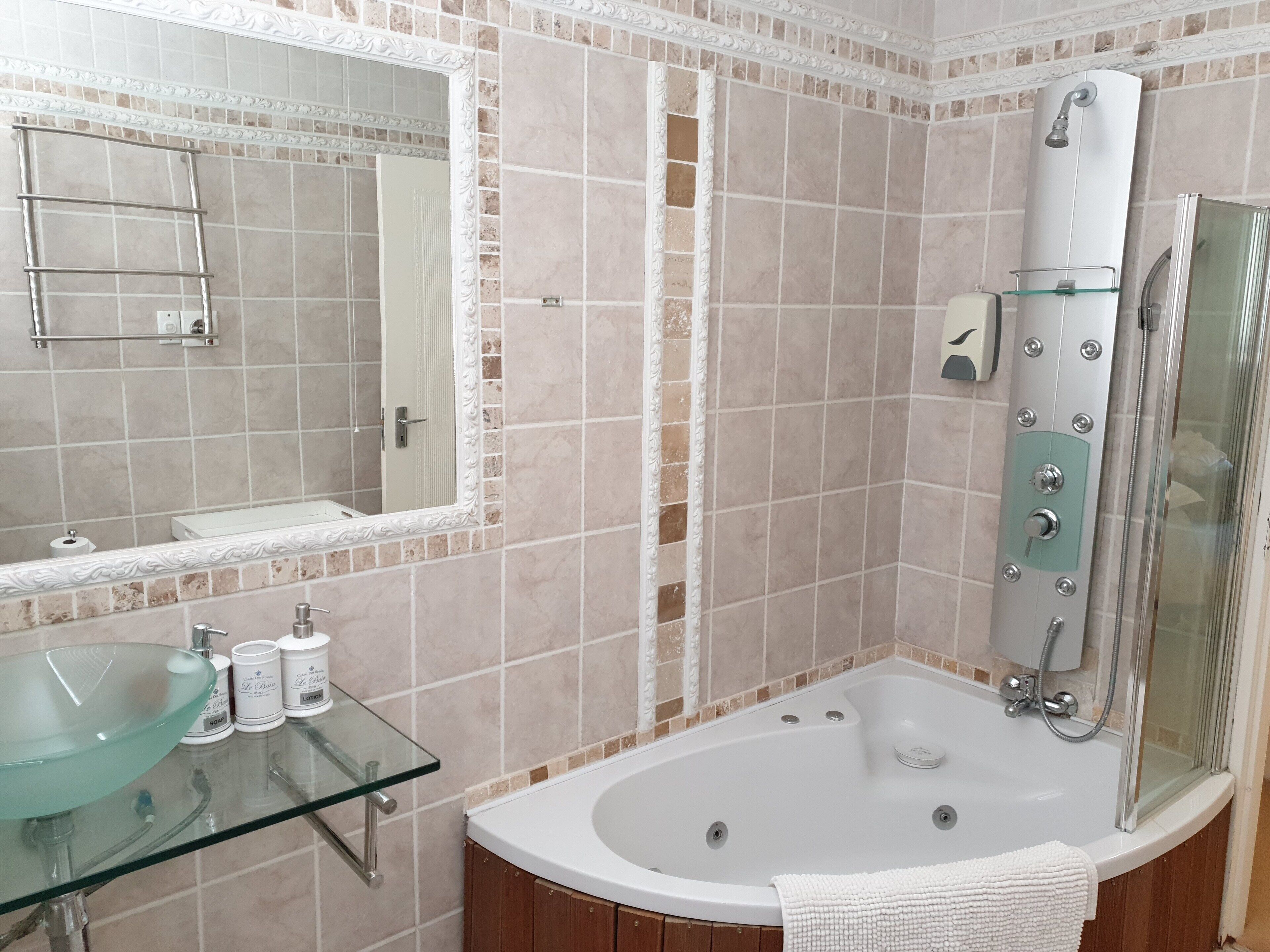 A bathroom with a glass sink, a large mirror, a bathtub, and a shower.