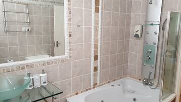 A bathroom with a glass sink, a large mirror, a bathtub, and a shower.