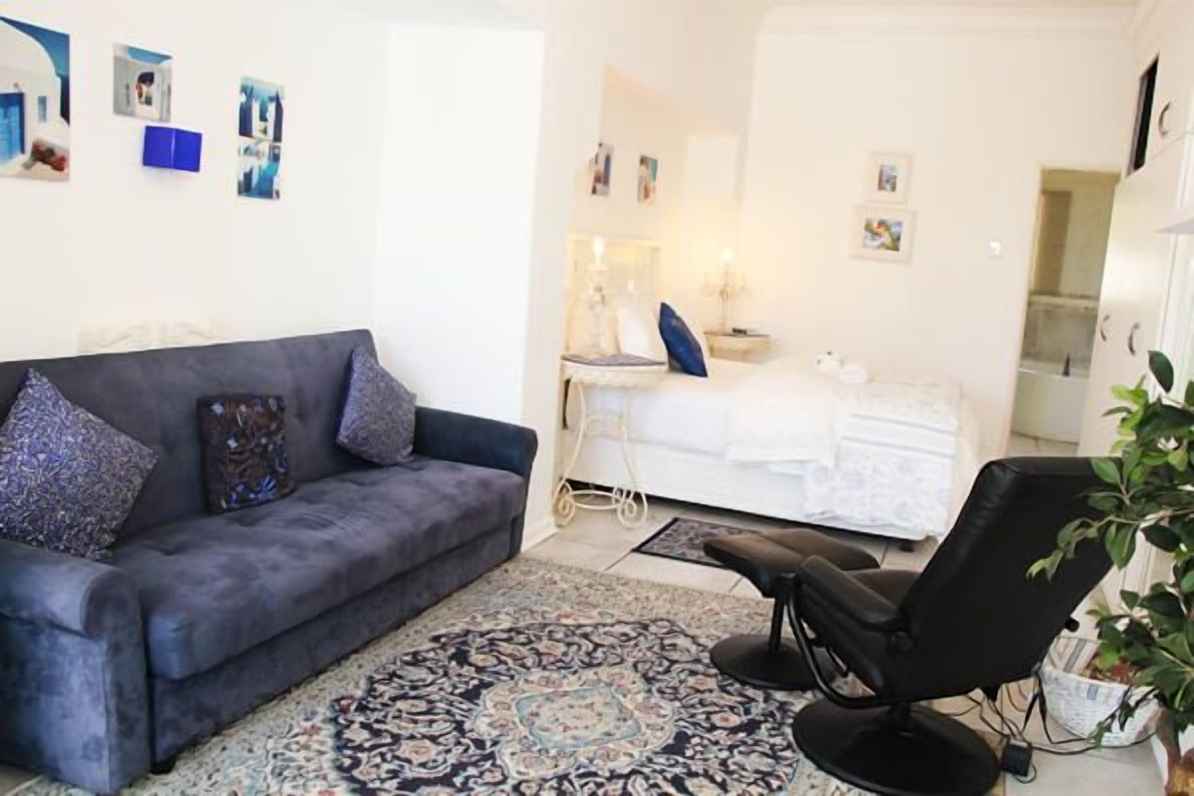 Una sala de estar moderna con un sofá gris, un sillón negro y una alfombra estampada.