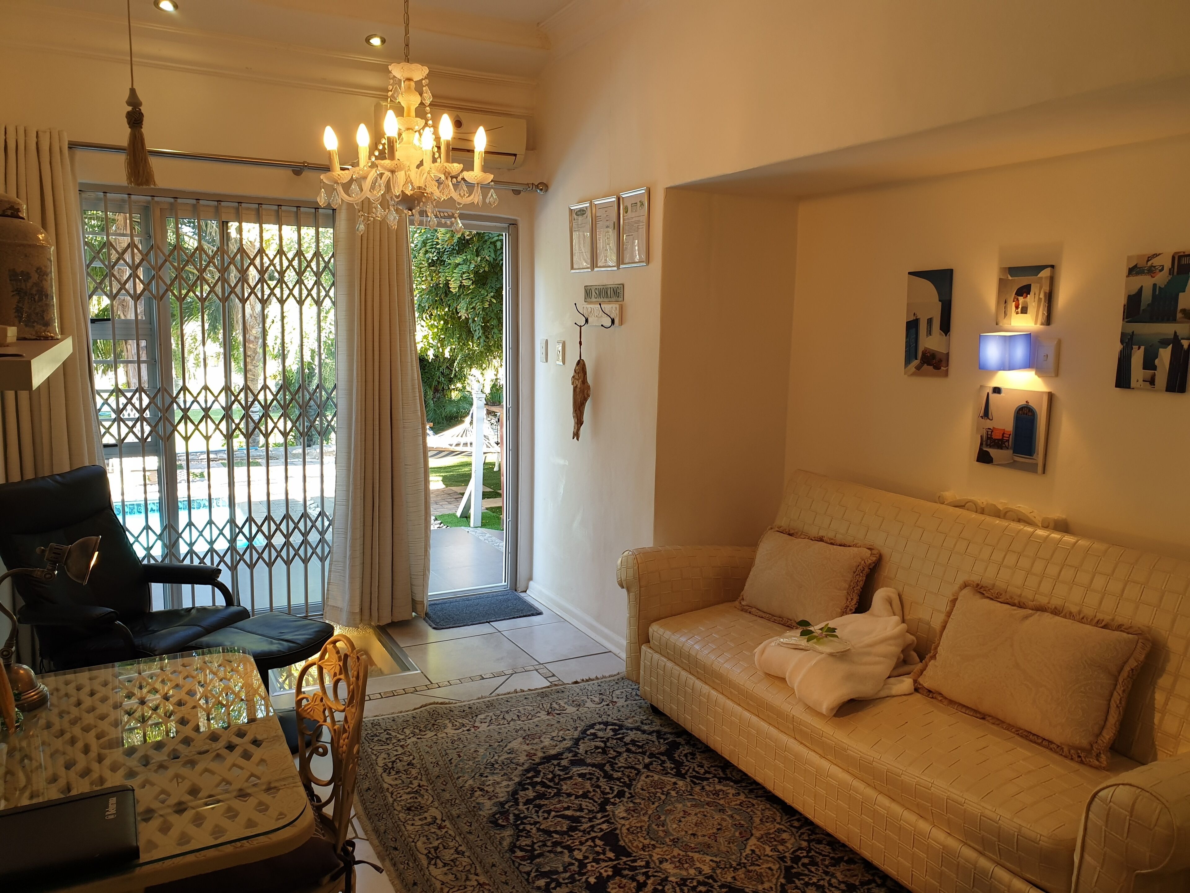 A living room with a beige sofa, a glass coffee table, and a chandelier.