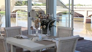 A dining area with wicker furniture and a view of a bridge over water.