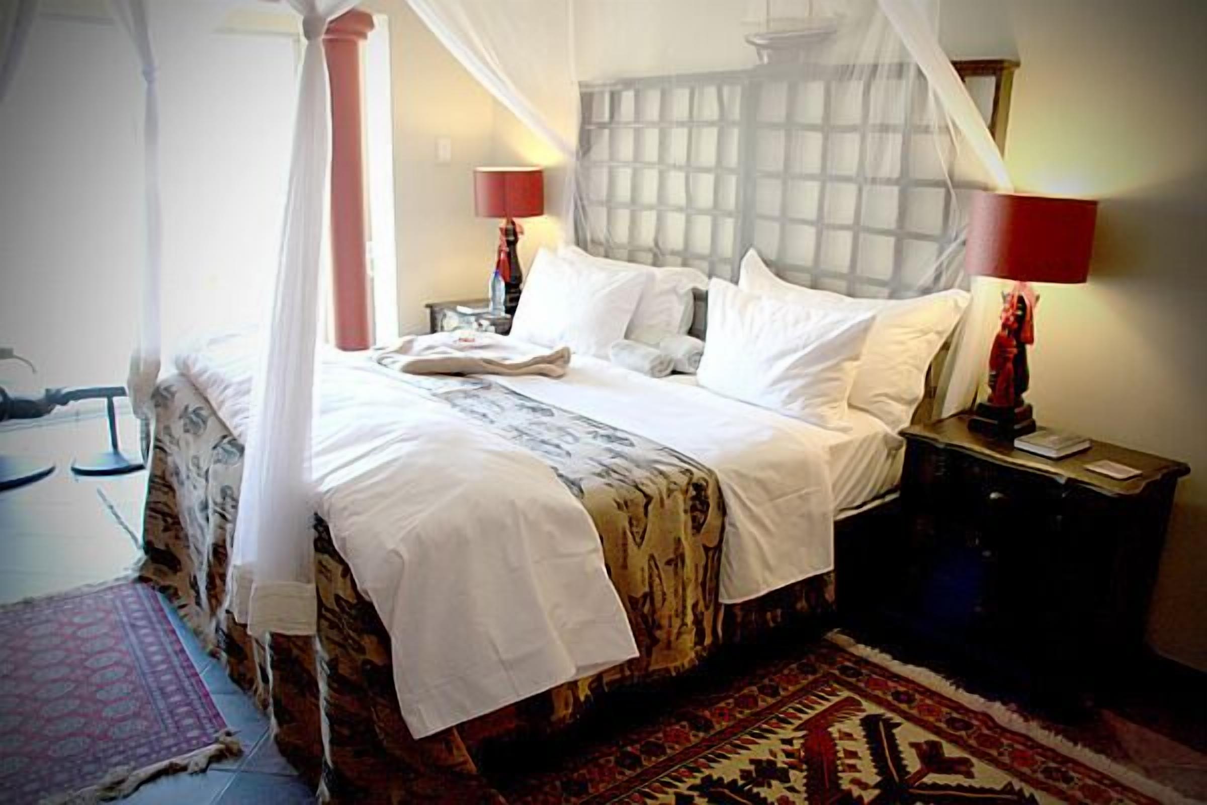 Una camera da letto con un letto a baldacchino, un comodino con una lampada e un tappeto decorato.