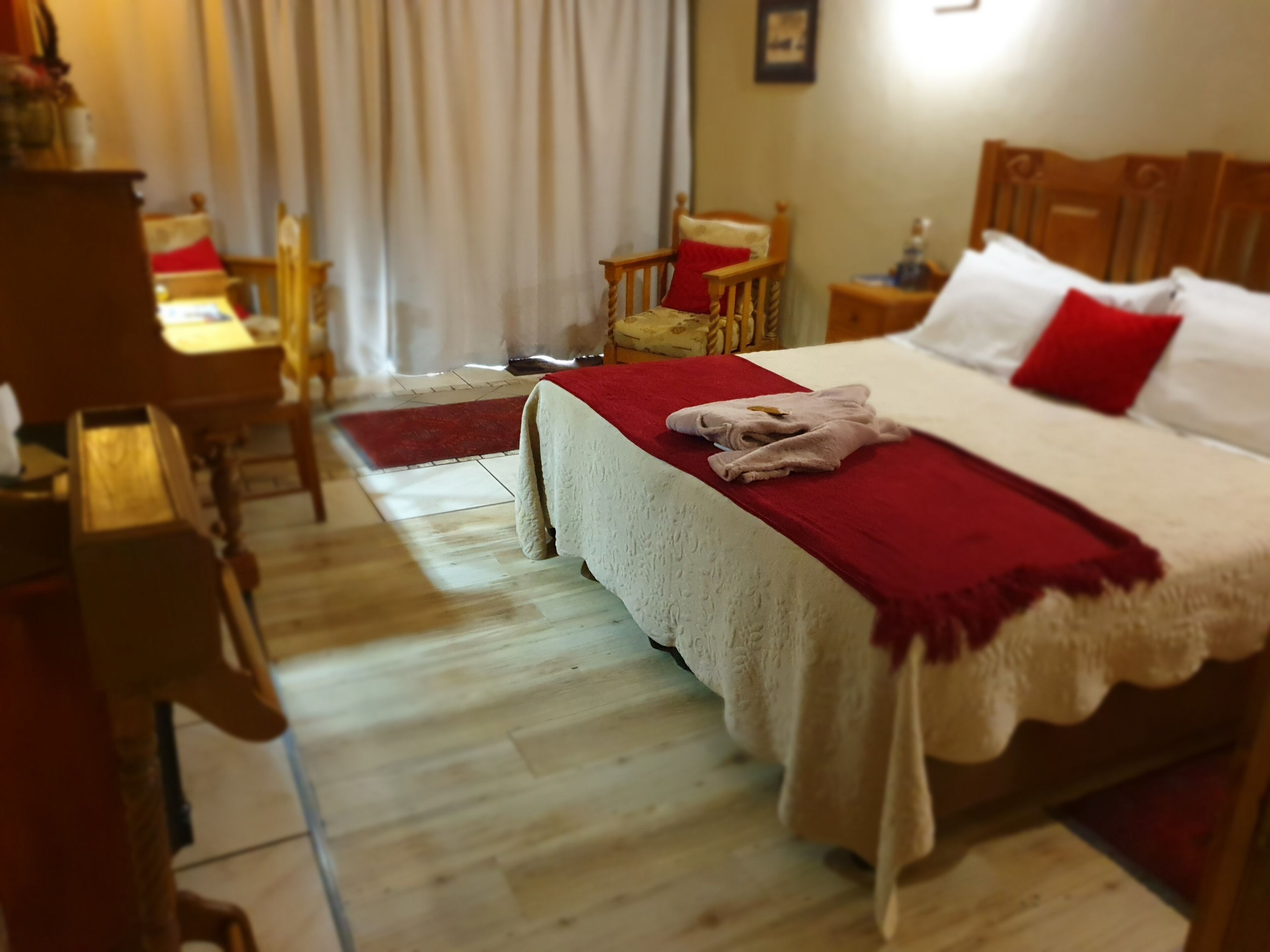 A hotel room with a bed, a desk, a chair, and a small table.