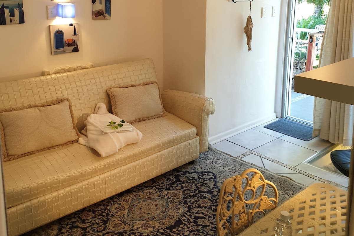 A cozy living room with a beige sofa, a patterned rug, and a chandelier.