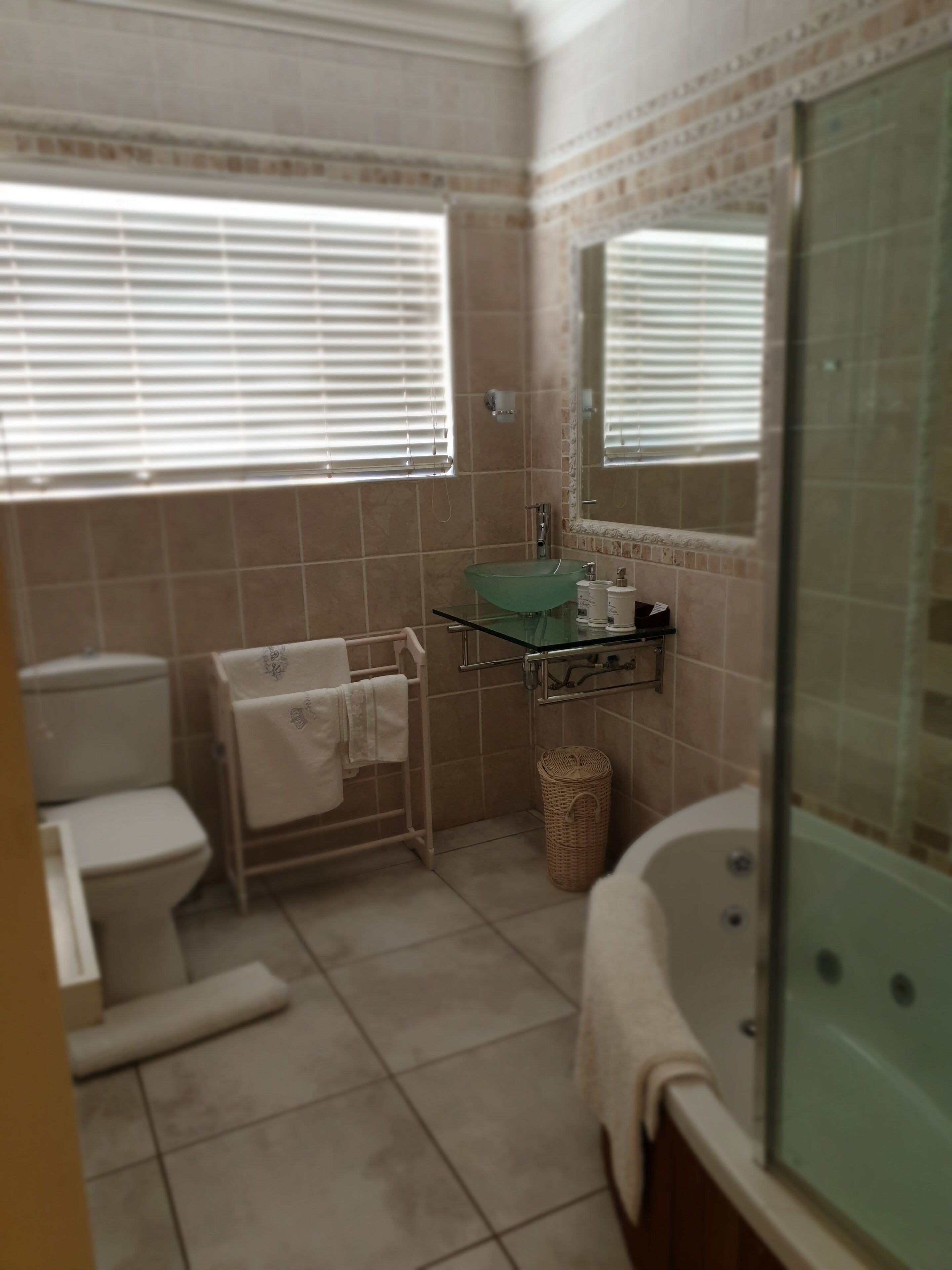 Un baño con inodoro, lavamanos de cristal, bañera y ducha.