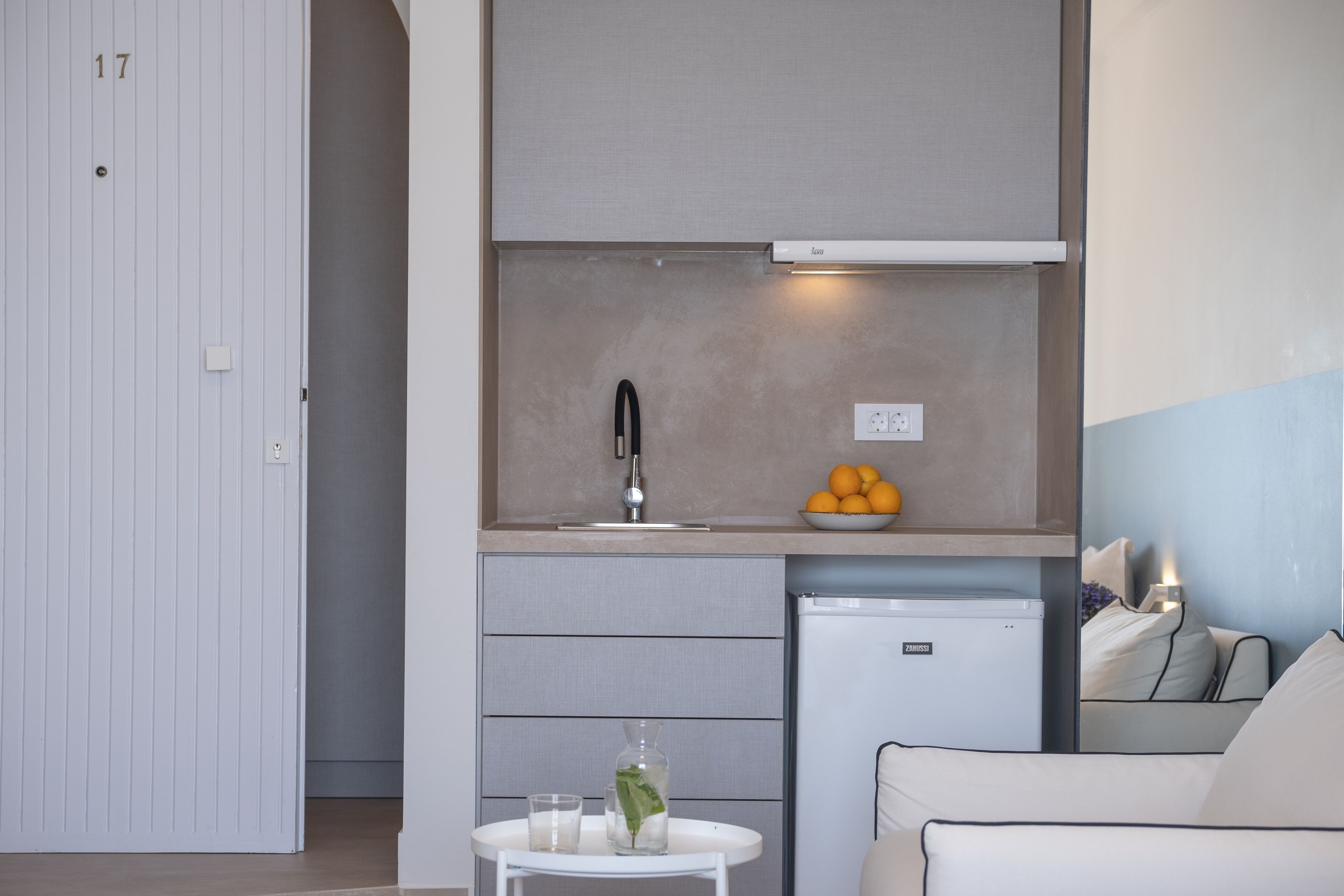 Una kitchenette compacta con horno integrado, un refrigerador pequeño y un lavamanos.