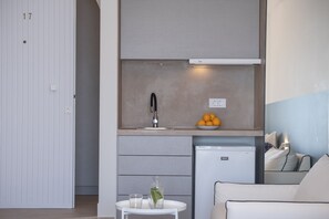 A compact kitchenette with a built-in oven, a small fridge, and a sink.